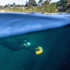 Photographie (de Tristant Keroullé) d'une femme sous l'eau avec un DeepFoil avec une vue sur la surface et la terre