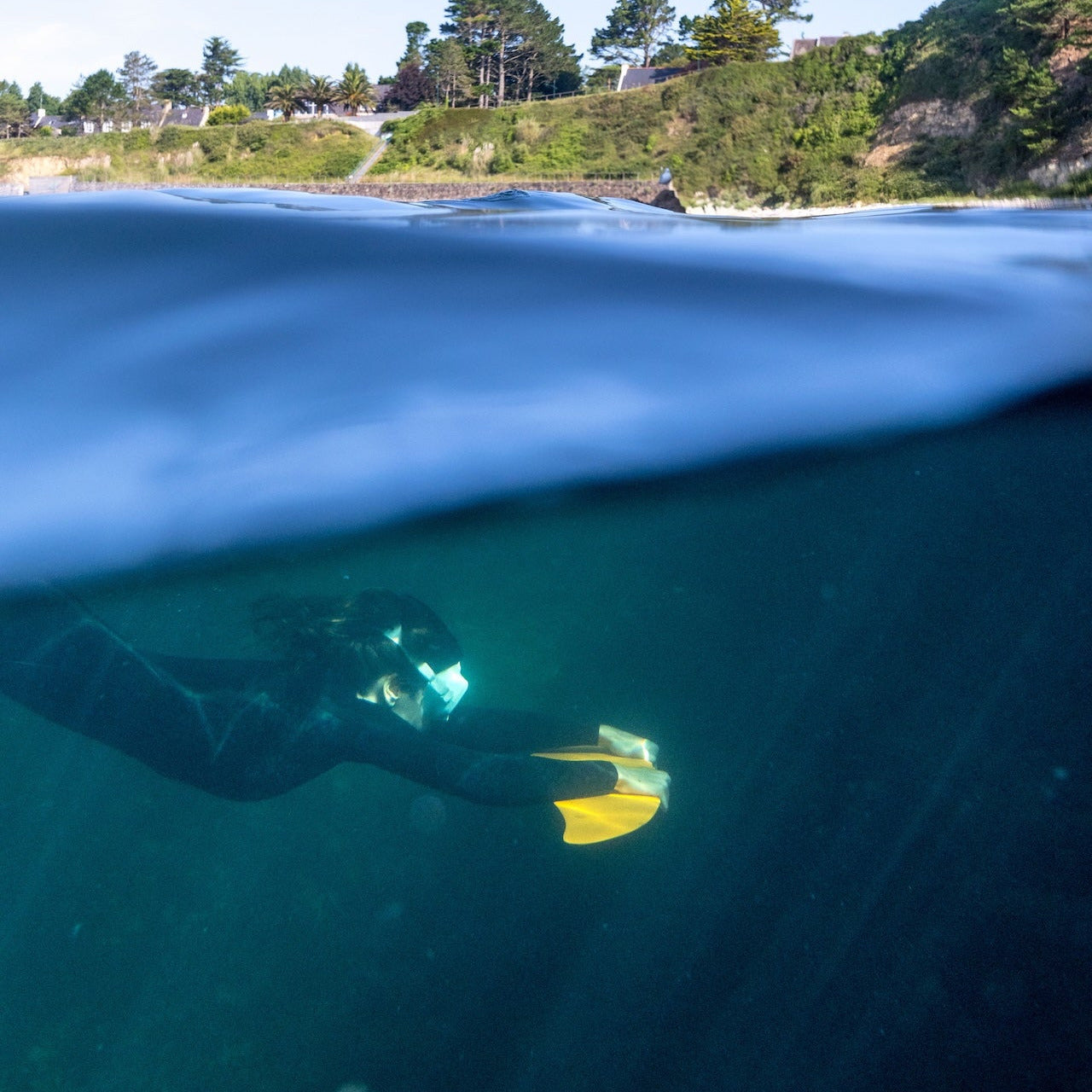 Photographie (de Tristant Keroullé) d'une femme sous l'eau avec un DeepFoil avec une vue sur la surface et la terre