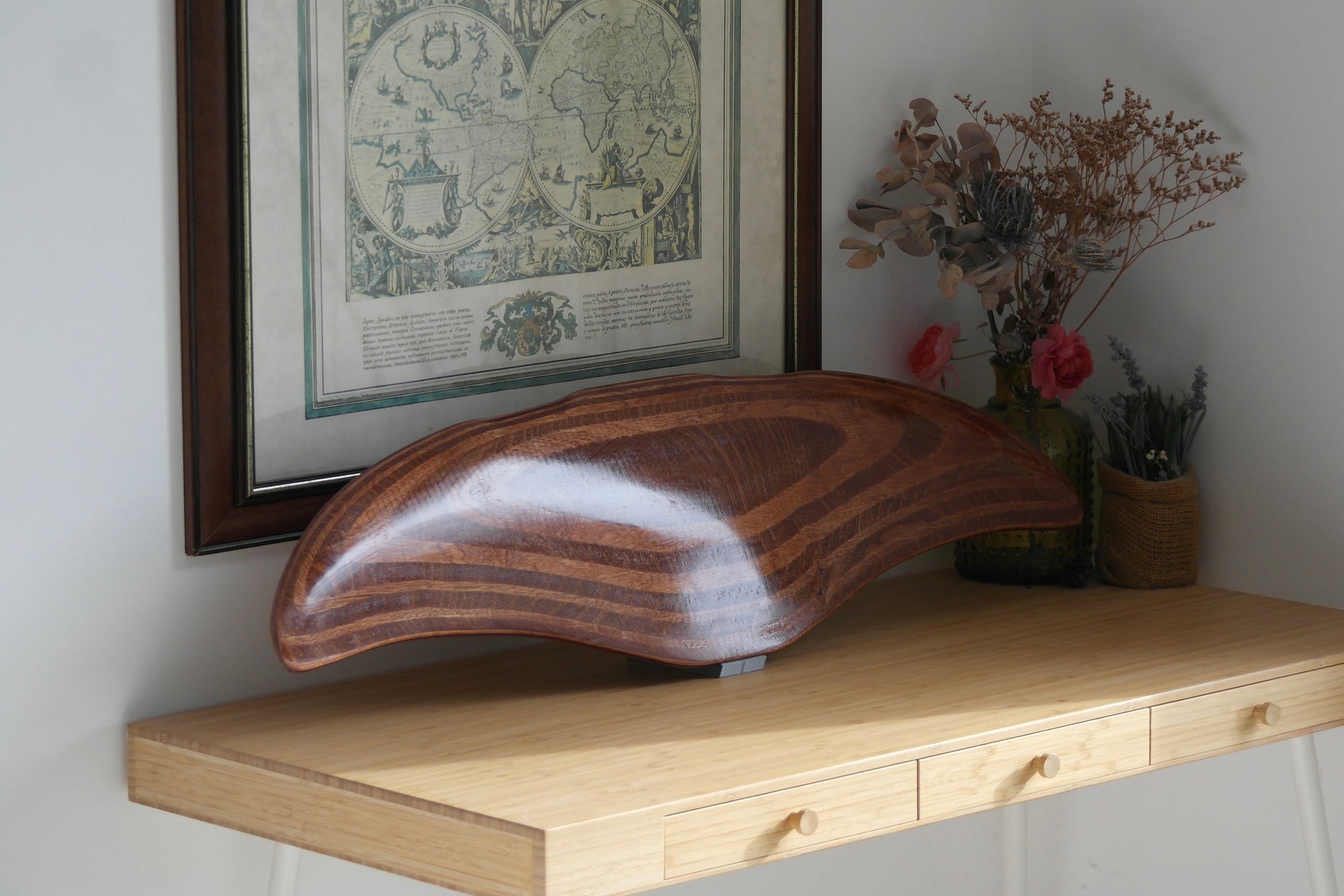 DeepFoil en bois (ou Deep Foil) présenté sur son support sur un bureau avec un rayon de soleil