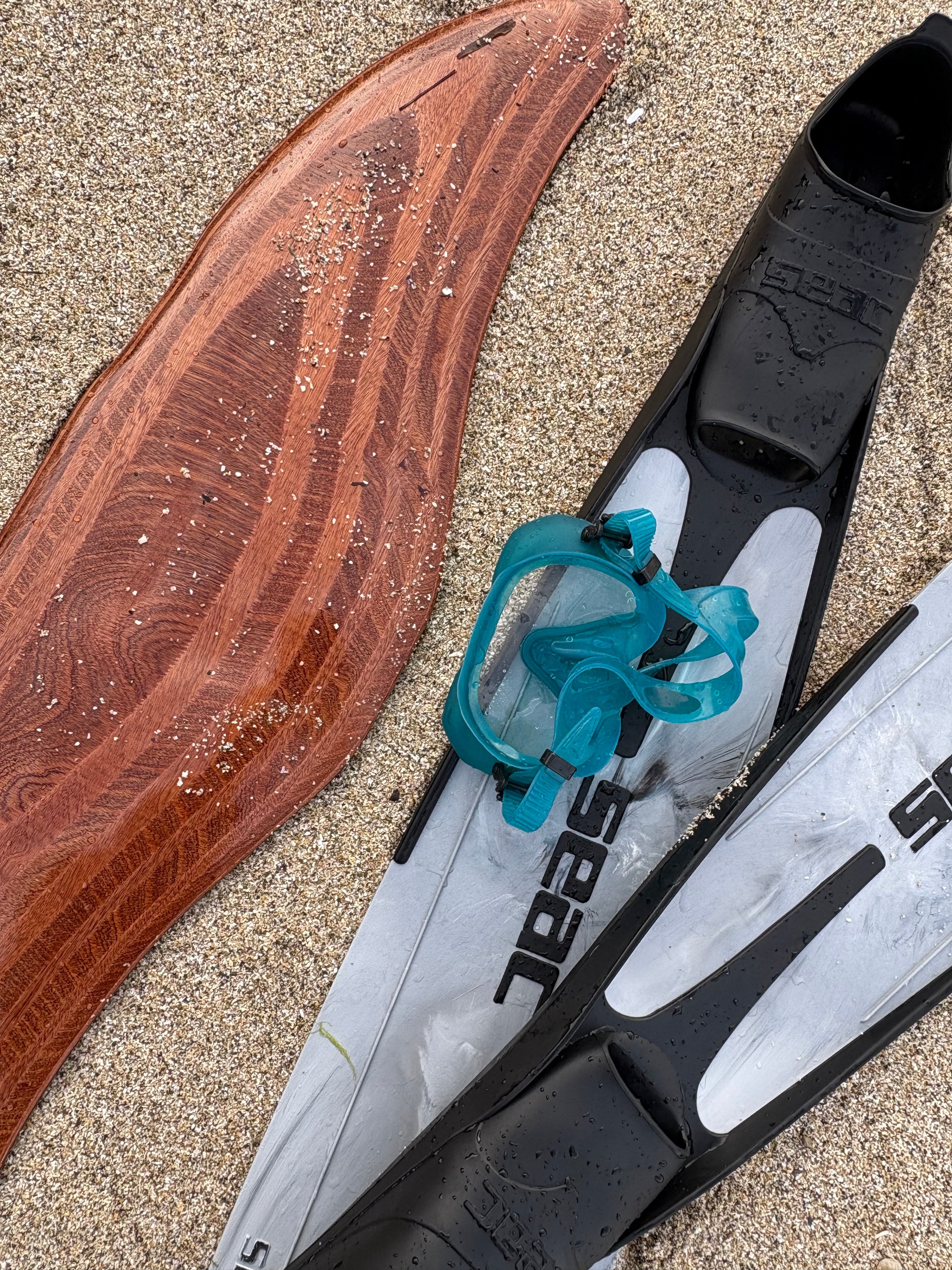 Deepfoil en bois pose sur la plage a cote de masque et de palmes