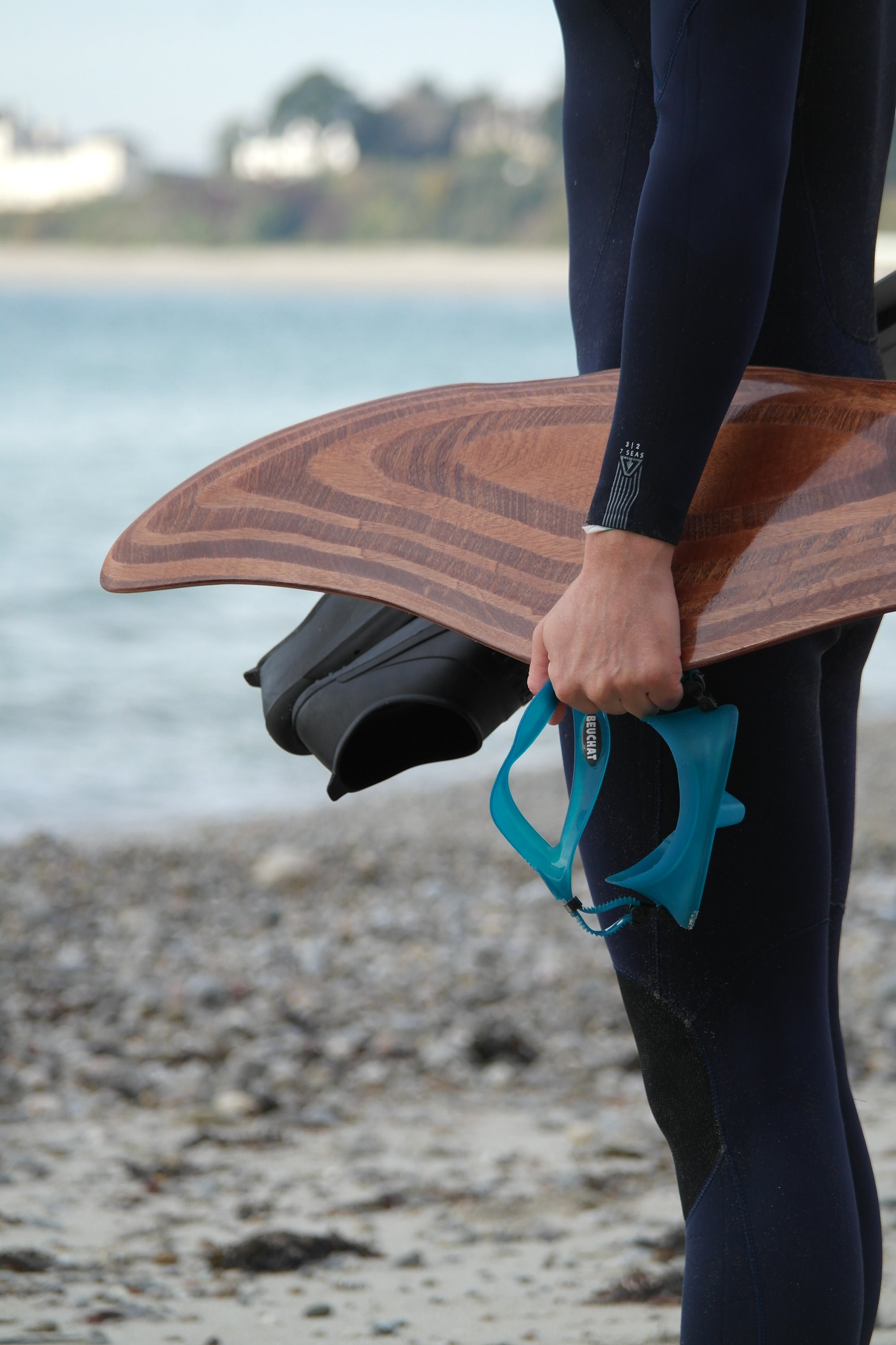 Plongeur ou pratiquant de snorkeling tenant un DeepFoil (ou DeepFoil) en bois face à la mer avec des palmes et un masque à la main ◦ Nereis ocean