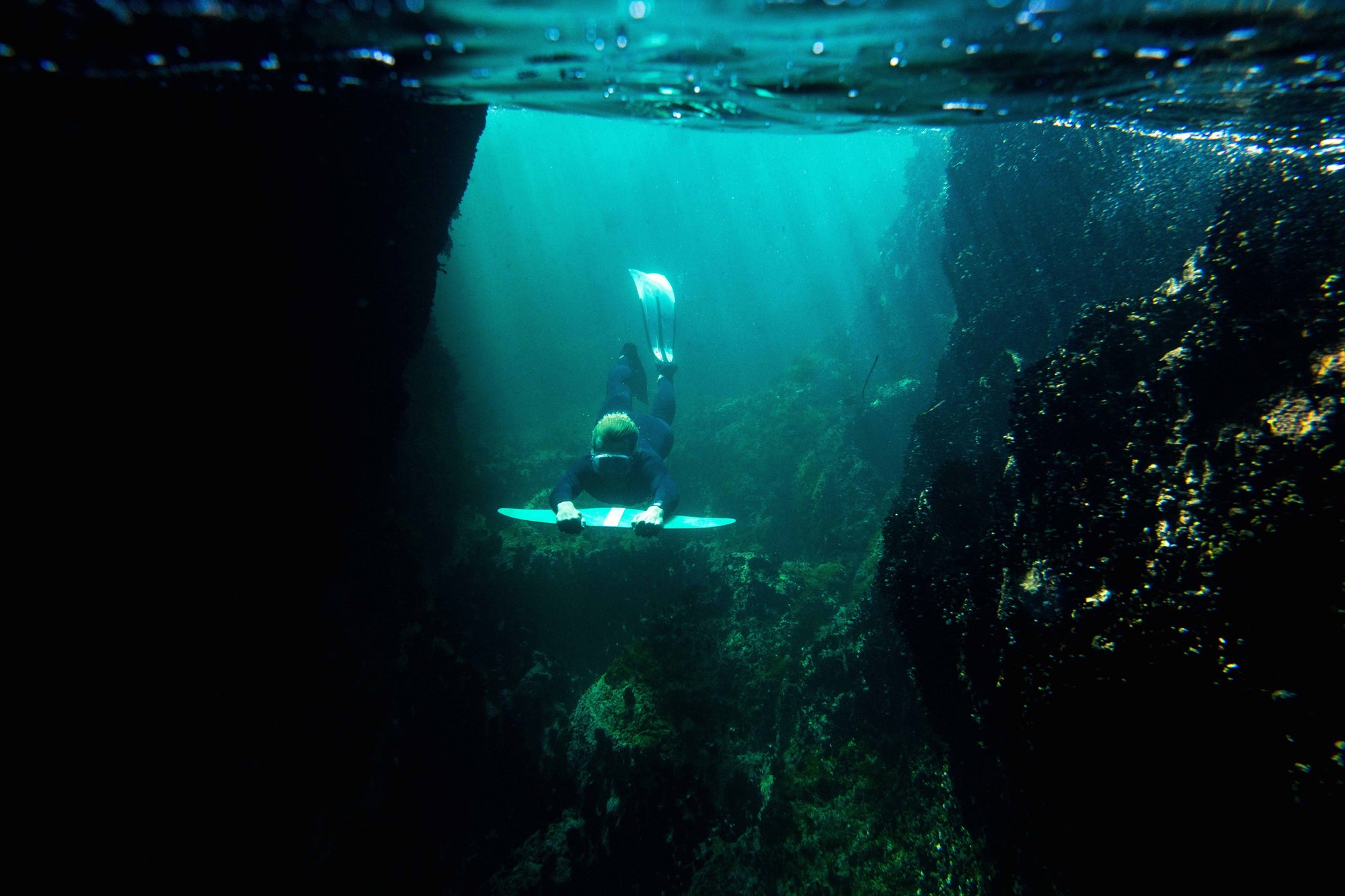 Photographie d'un plongeur utilisant un DeepFoil dans un canyon sous marin illuminé par le soleil à travers la surface